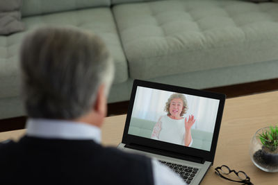 Rear view of man using laptop on table