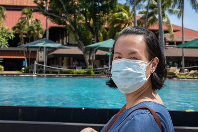 Portrait of woman wearing mask while standing by swimming pool