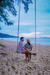 Rear view of couple sitting on beach