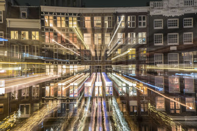 Light trails on road amidst buildings in city at night