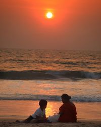 Rear view of people at beach during sunset