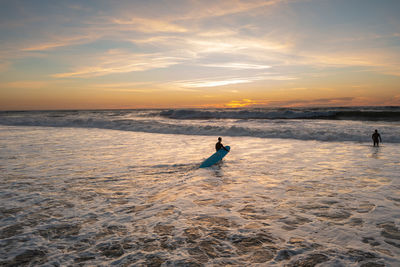 Silhouette man walking at beach against sky during sunset