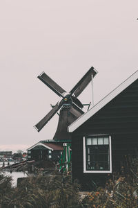 Traditional windmill by house against clear sky