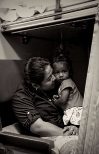 Rear view of mother and girl sitting at home