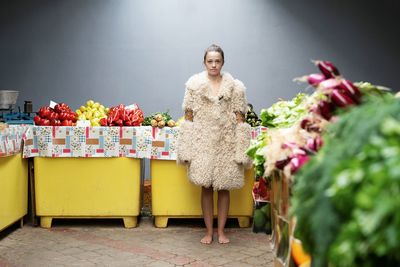 Portrait of young fashion model standing against vegetables