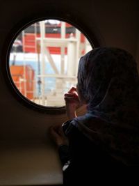 Rear view of woman looking through window