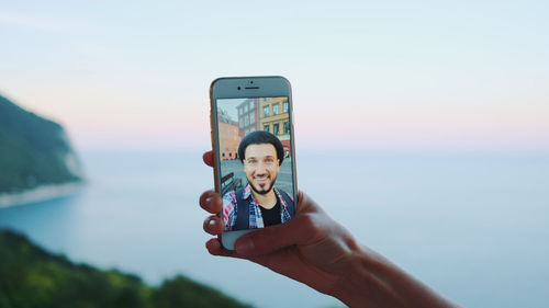 Cropped hand of woman holding mobile phone with man photo
