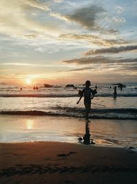 Man on beach against sky during sunset