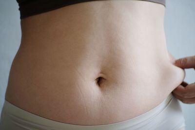 Midsection of woman standing on bed