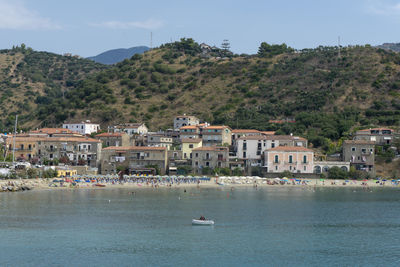 Scenic view of sea by townscape against sky