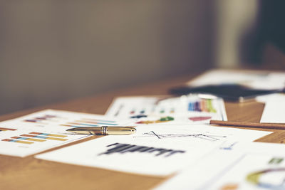 Close-up of graphs with pen on desk in office