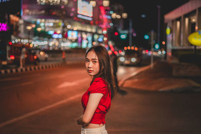 Portrait of woman standing in illuminated city at night