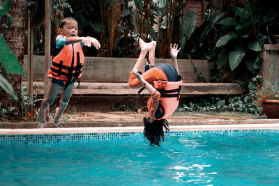 Siblings jumping in swimming pool