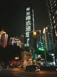 Illuminated street amidst buildings in city at night