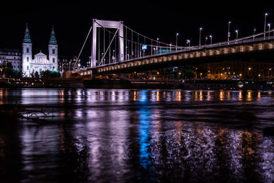 Illuminated bridge over river at night