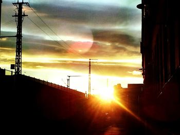 Low angle view of electricity pylon at sunset