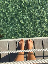 Low section of woman standing at the edge of jetty over sea