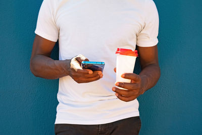 Close up of a black man using the phone and with a coffee to go. takeaway coffee and technology concept.