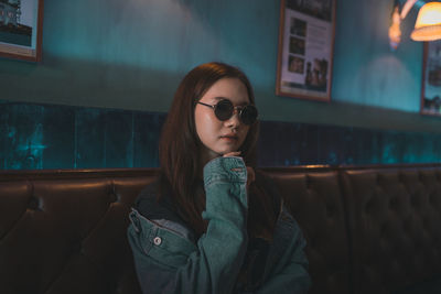 Young woman looking away while sitting on window