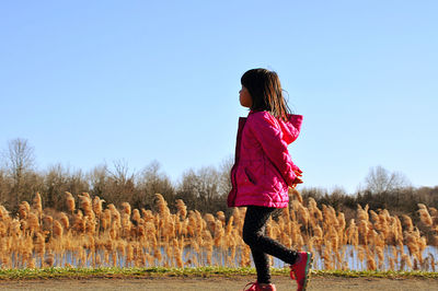 Rear view of girl standing on field against clear sky