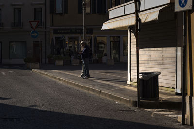 Man walking on footpath by road in city