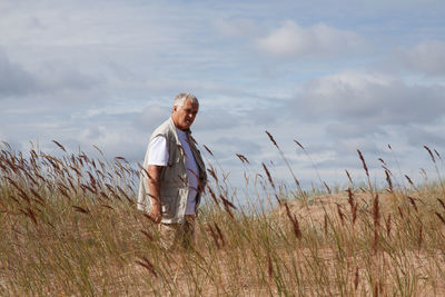 Mature man standing on field against sky