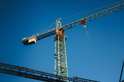 Low angle view of crane against clear blue sky