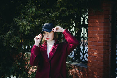 Young woman looking away while standing against plants