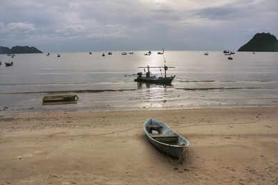 Boat moored on beach against sky