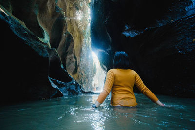 Rear view of woman on rock in water