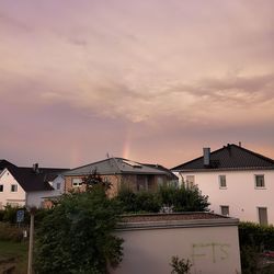 House and buildings against sky at sunset