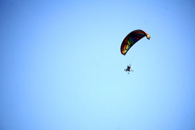 Low angle view of person paragliding against clear blue sky