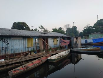 Boats moored by lake against sky