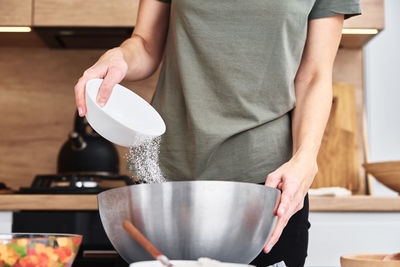 Woman in the kitchen cooking a dough. hands pour flour into a bowl