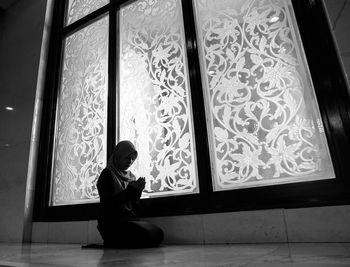 Side view of woman sitting on floor at home