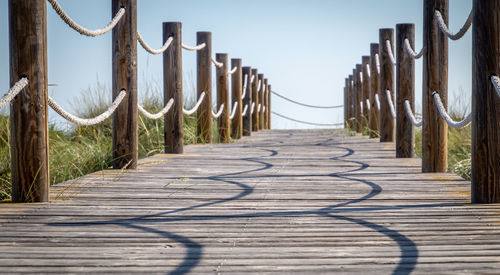 Surface level of wooden boardwalk against sky