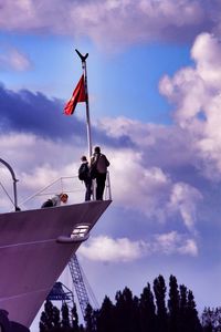 Low angle view of flags against cloudy sky