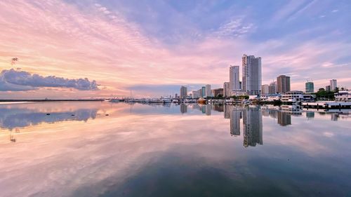 Scenic view of sea and buildings against sky during sunset
