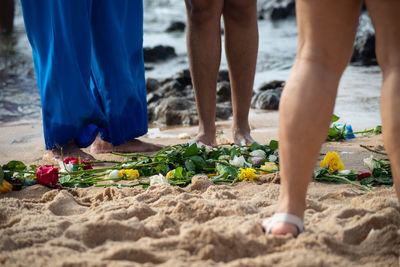 Lower part of the legs of unidentified people on the beach. tribute to iemanja.