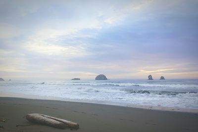 View of calm beach against cloudy sky