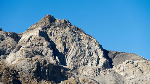 Low angle view of rock formation against clear blue sky