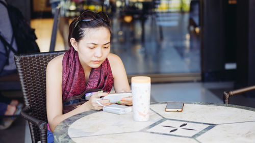 Close-up of man using mobile phone while sitting on table