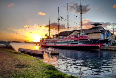 Boats moored at harbor during sunset