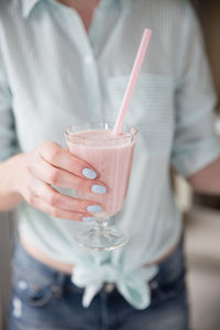 Midsection of woman holding drink in glass