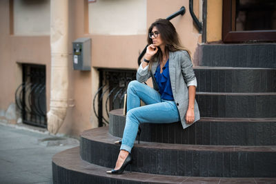 Full length of woman sitting on staircase