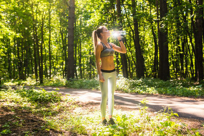 Woman standing by tree trunks in forest