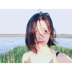 Beautiful young woman at beach against clear sky