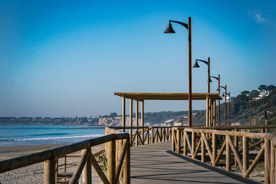 Pier over sea against clear blue sky