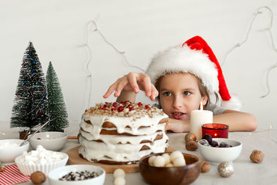 Preparing food for christmas dinner boy in red santa hat wants to steal piece of christmas cake