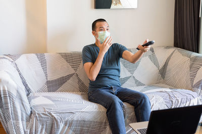 Full length of man sitting on sofa at home